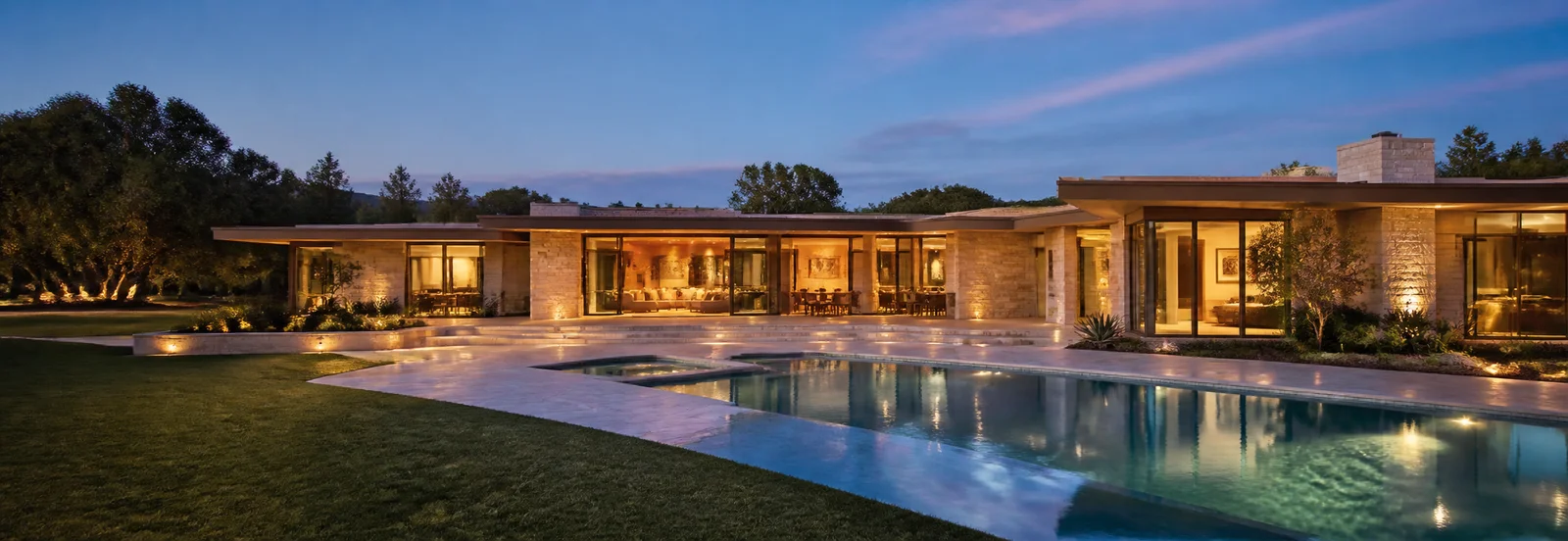 Modern luxury home with warm interior lighting and a pool